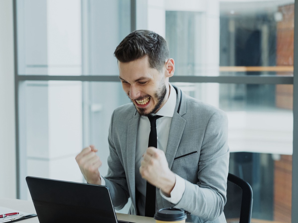 Business owner celebrating a booked appointment at his laptop